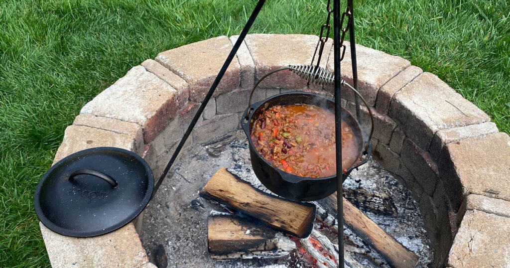 cast iron pot full of venison chili cooking over open fire