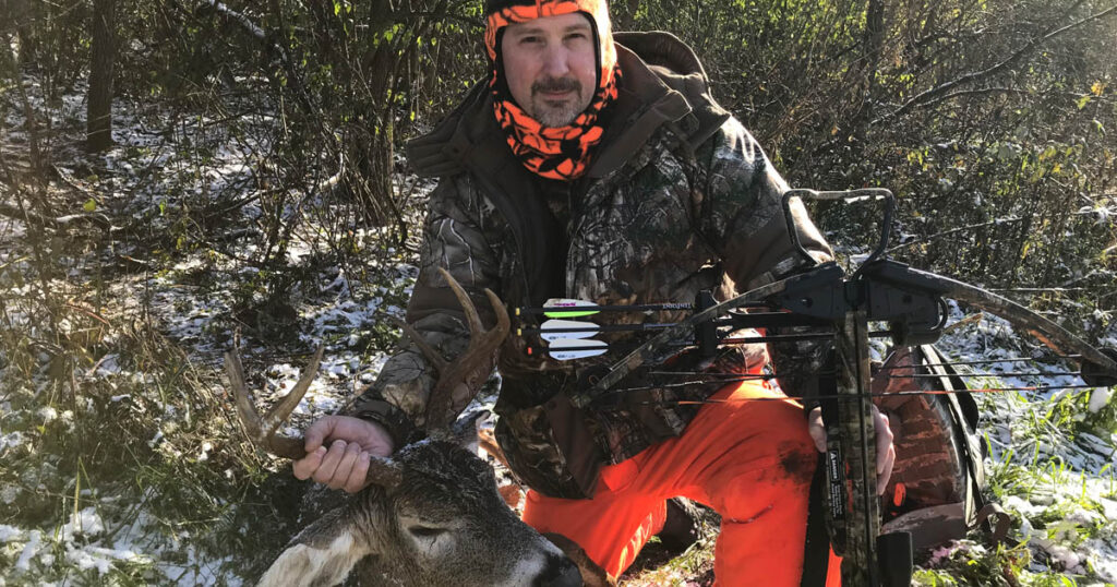 hunter with crossbow next to deer just shot